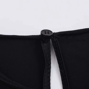 Détail du chemisier en dentelle noire montrant un bouton à quatre trous et le tissu sergé