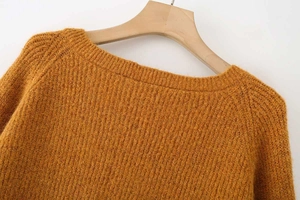 Detail view of mustard yellow chunky knit sweater neckline on a wooden hanger