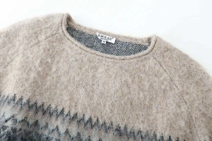 Detail of soft knit texture with geometric pattern and woven neck label on sweater