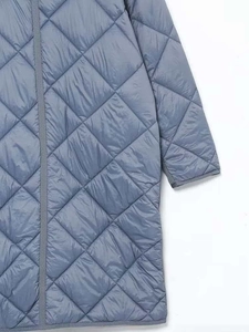 Dettaglio del cappotto trapuntato blu grigio con cuciture a diamante e finitura satinata