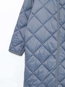 Dettaglio del cappotto trapuntato grigio-blu con cuciture a diamante e bordi rifiniti