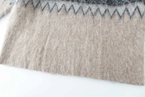 Detailed macro view of soft knit texture with gray jacquard pattern on oatmeal sweater