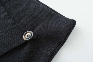 Close-up of black knit fabric texture with a brown amber pattern button detail