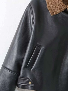 Detail of black faux leather jacket with brown sherpa collar and golden button accents
