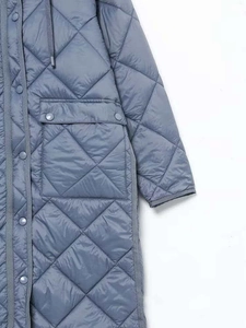 Dettaglio del cappotto lungo trapuntato grigio-blu con cappuccio, bottoni e tasche