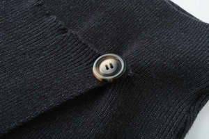 Macro shot of a marbled brown button on black knit fabric with detailed stitching