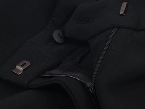 Close-up of black suit pants waist showing button, metal hook, and zipper details