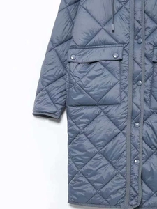 Dettaglio del cappotto trapuntato con cappuccio, bottoni automatici e tasche con patta