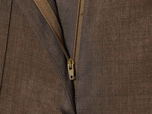 Detailed close-up of the high-quality golden metal zipper on khaki wool blend trousers