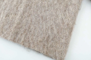 Macro texture of beige jacquard knit sweater showing plush mohair wool fiber detail