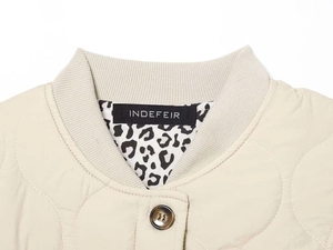 Detail view of beige quilted jacket with ribbed collar and leopard print lining
