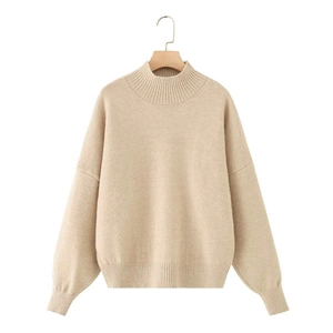 Detail of ribbed cuffs and hem on a loose apricot mock neck knit sweater