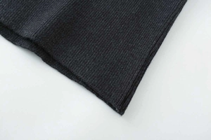 Detailed macro view of dark grey rib-knit texture and hemline on long knit skirt