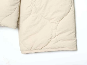 Detail shot of beige quilted jacket with precision stitching and gourd pattern texture