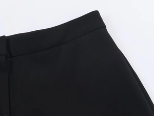 Detail shot of black high-waisted trousers showing fabric texture and fine stitching
