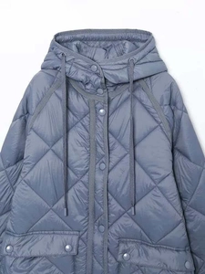 Dettaglio del parka invernale trapuntato blu-grigio con cappuccio e grandi tasche
