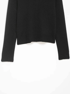 Détail du pull en maille noire montrant l'ourlet et les poignets côtelés de qualité