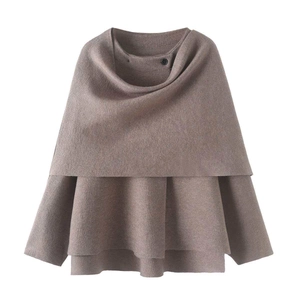 Detail of tan knit poncho with turtleneck button detail and layered asymmetrical hemline