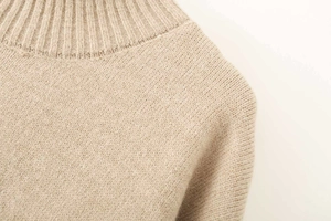 Detail of oatmeal ribbed knit sweater showing the soft texture and turtleneck collar