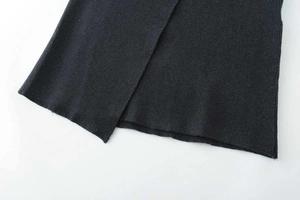 Detailed close-up of dark grey flat-knit fabric with asymmetric slit and neat stitching