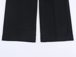 Close-up of black wide-leg trousers hem featuring high-quality draping and clean tailoring