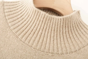 Detail shot of ribbed crew neck on soft beige knit sweater with warm wool texture