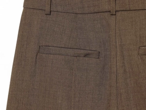 Macro detail of khaki green wool trousers showing the waistband, belt loops, and rear pocket