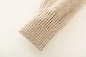 Detailed macro view of soft beige knitted sweater with elastic ribbed cuff texture