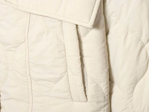 Macro detail of cream onion-quilted jacket fabric and a vertical side pocket