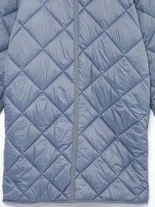 Dettaglio del cappotto trapuntato azzurro con cuciture a rombi e chiusura a cerniera