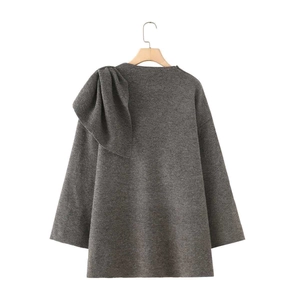Detail of grey knitted sweater featuring a large stylish bow on the right shoulder