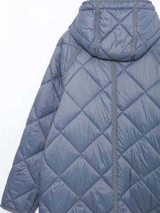 Dettaglio della trapuntatura a rombi e cappuccio sul cappotto invernale grigio-blu