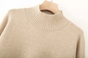 Detailed close-up of apricot ribbed mock neck knit sweater on a wooden hanger