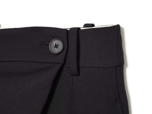 Close-up of high-waisted black wide-leg trousers showing button detail and twill fabric