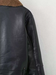 Detail view of black faux leather biker jacket with brown faux shearling collar and silver button