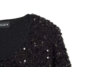 Detail der schwarzen Strickjacke mit Pailletten, V-Ausschnitt und glänzender Textur