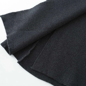 Minimalist asymmetrical knit skirt in dark grey showing thick ribbed fabric texture