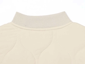 Detail of knitted ribbed collar and wavy quilted fabric on a beige winter jacket