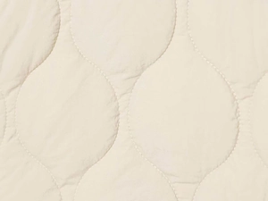 Close-up of beige quilted fabric detail featuring classic gourd pattern stitching