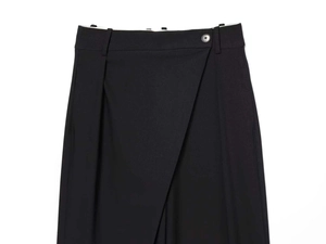 Detail of black wide-leg trousers featuring asymmetrical wrap waist and button closure