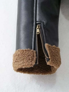 Close-up of black leather jacket cuff with gold zipper and brown shearling lining