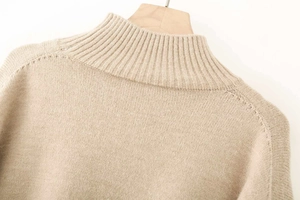 Detail of mock neck collar on beige ribbed knit sweater with soft texture
