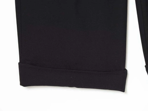 Detailed macro view of wide folded hems on black wide-leg woven trousers for women