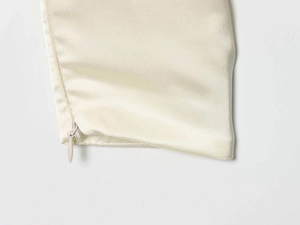 Nahaufnahme des verdeckten Reißverschlusses an der eleganten cremefarbenen Satinbluse
