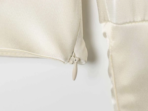 Detailaufnahme des verdeckten Reißverschlusses an einer cremefarbenen Satinbluse