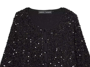Detailaufnahme der schwarzen Paillettenjacke mit V-Ausschnitt, Knöpfen und Markenetikett
