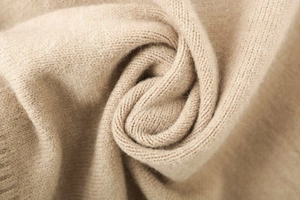 Macro shot of high-quality oatmeal knit fabric showing soft texture and fine stitches