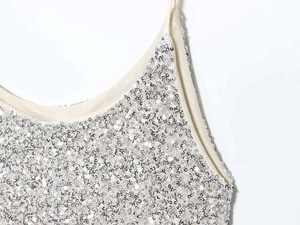 Detail shot of shimmering silver sequins and thin straps on a summer camisole dress