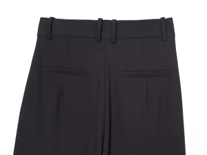 Detail of high-waist black wide-leg trousers showing back welt pockets and stitching