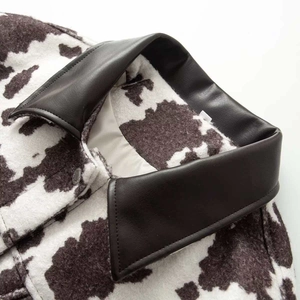 Fashionable faux fur cow print jacket featuring a black leather collar and metal button